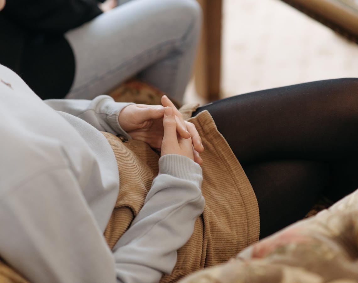 Close-up of a teenager's hands clasped in a counseling session, symbolizing contemplation.